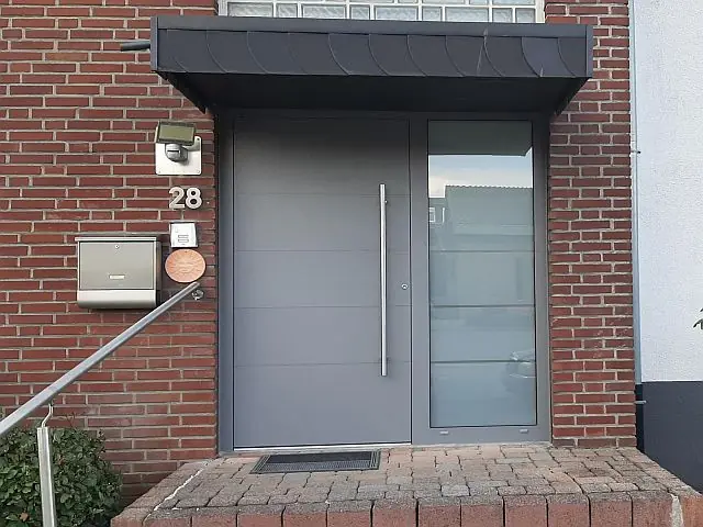Graue Aluminium-Haustür mit Seitenteil und Vordach, montiert von Metallbau Hendricks in Kleve