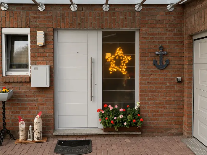 Weiße Aluminium-Haustür mit Glas-Seitenteil an einem Klinkerhaus, eingebaut von Metallbau Hendricks