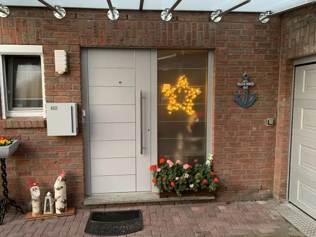 Weiße Aluminium-Haustür mit Glas-Seitenteil an einem Klinkerhaus, eingebaut von Metallbau Hendricks